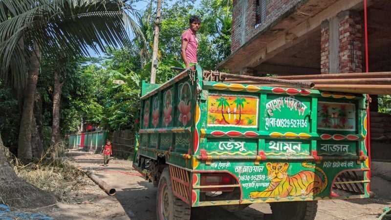 Man standing on truck bed in third world country