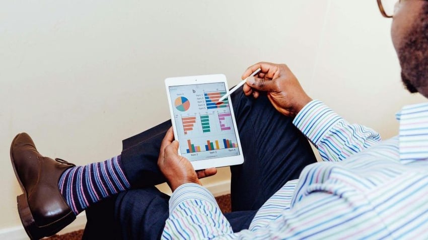 Man in suit looking at charts on iPad