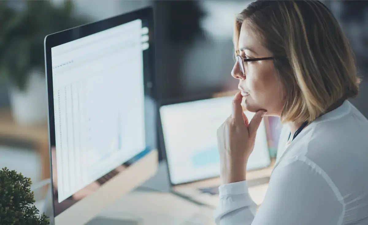 An educated lady, sitting at a desk on her computer reviewing investment portfolios.