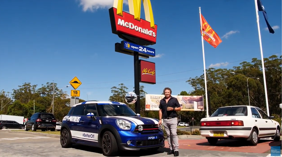 Mark Halford standing next to a Kelly+Partners Mini Cooper car, outside his McDonald's store.